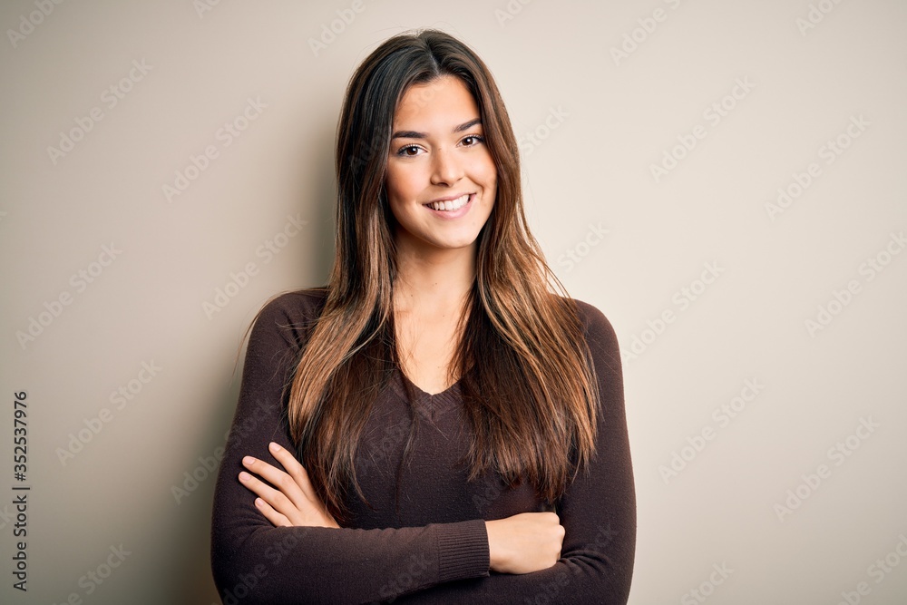 Young beautiful girl wearing casual sweater standing over isolated white background happy face smiling with crossed arms looking at the camera. Positive person. - obrazy, fototapety, plakaty 