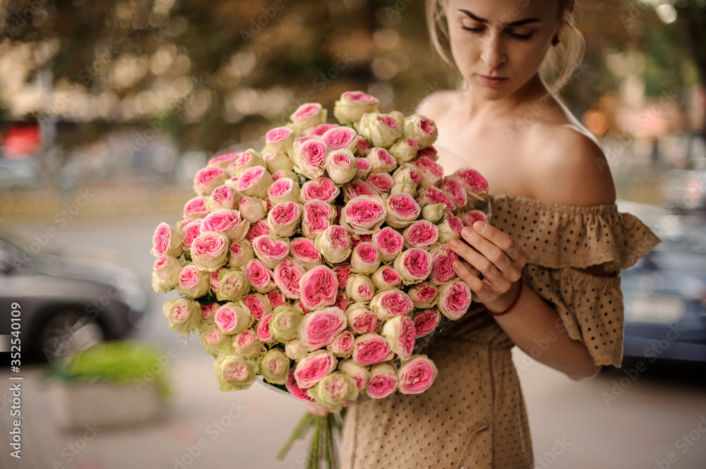 Fototapeta premium Young woman holds huge bright bouquet of ranunculus flowers