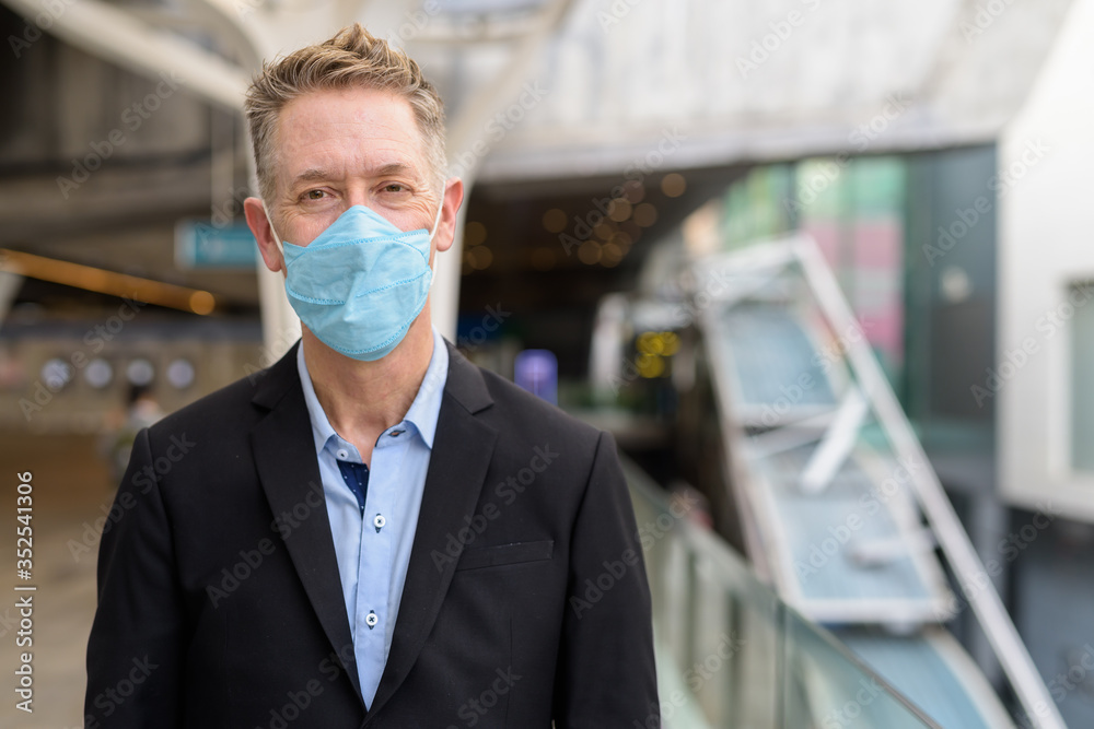 Mature businessman wearing mask for protection from corona virus outbreak at the footbridge