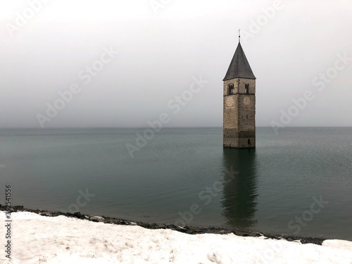 Tower of church in the lago di resia lake during foggy morning