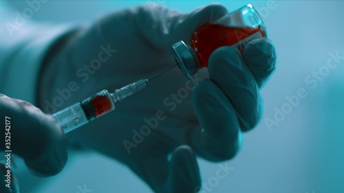 the doctor draws into a syringe a vaccine from the virus covid19 in the lab close-up