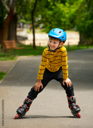 A nice and smiling boy rests a little after walking with the roller skates in the park