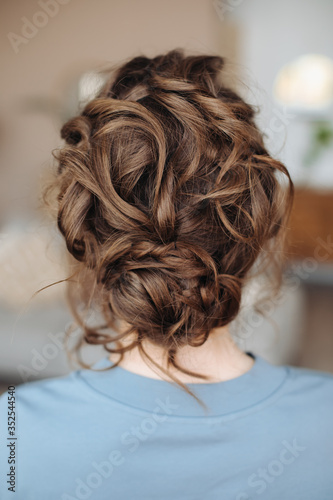 Complex hairstyle on the head of a brown-haired woman, Fashionable professional women's hairstyle. Evening look.
