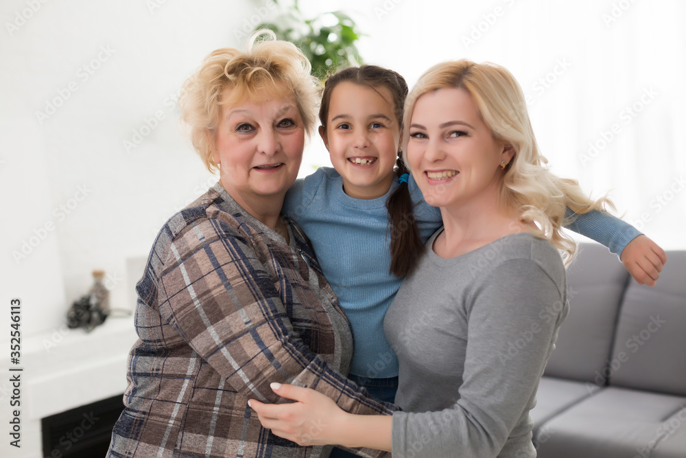 Portrait of three generations of women look at camera posing for family picture, cute little girl hug mom and granny enjoy time at home, smiling mother, daughter and grandmother spend weekend together Portrait of three generations of women look at camera posing for family picture, cute little girl hug mom and granny enjoy time at home, smiling mother, daughter and grandmother spend weekend together