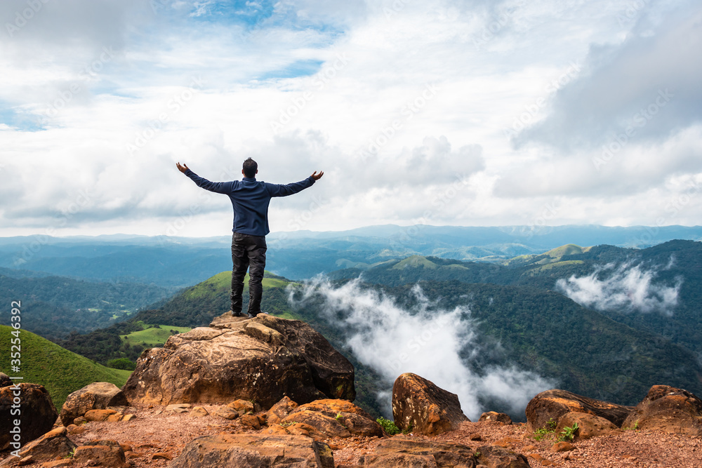 Obraz premium man isolated watching the serene nature at hill top with amazing cloud layers in background