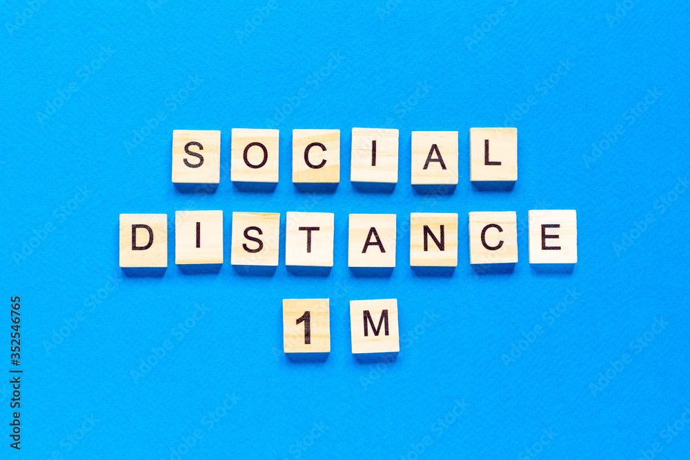 Words social distance 1 m. Wooden inscription on a blue background. Information sign of social distance 1 m from blocks on a blue background. Words social distance 1 m. Wooden inscription on a blue background. Information sign of social distance 1 m from blocks on a blue background.