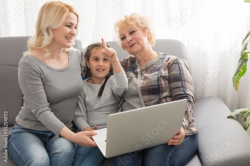 Grandmother and daughter teaching child use laptop application, playing game