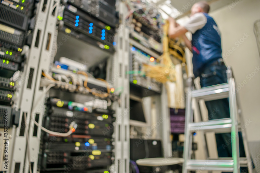 Blurred image of a server room. Technician standing on the stairs working in a data center. Blur background. No focus.
