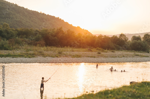 view of sunset in mountains above people swimming in river