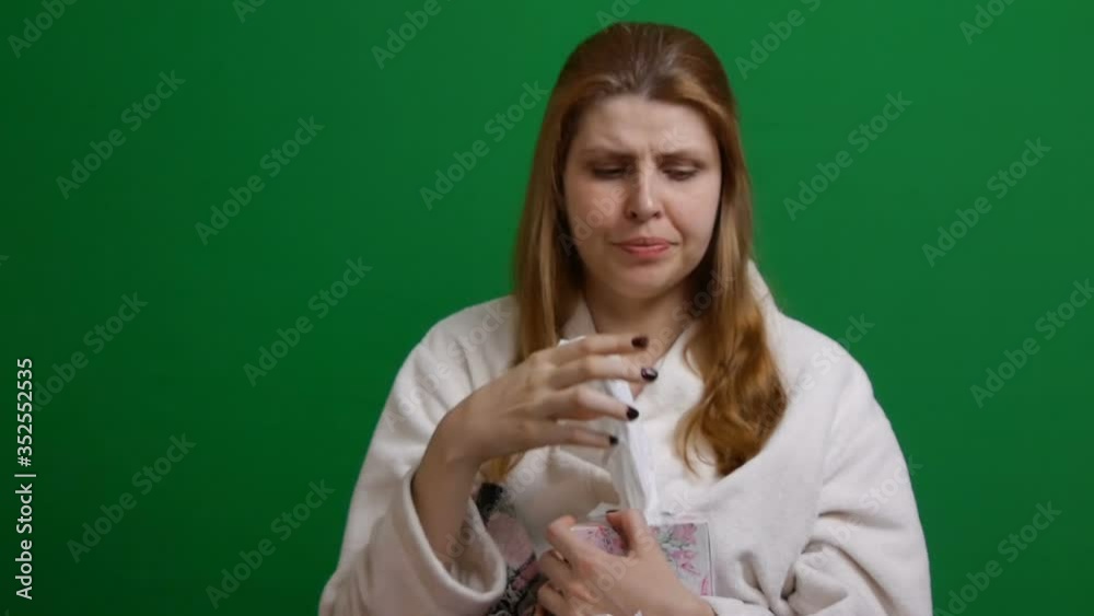 Sick woman wrapped in warm blanket. Cough. Coughing. Sore throat. COVID Danger of coronavirus pandemic 2019-ncov. Shot on a green isolated background. Sick woman wrapped in warm blanket. Cough. Coughing. Sore throat. COVID Danger of coronavirus pandemic 2019-ncov. Shot on a green isolated background.