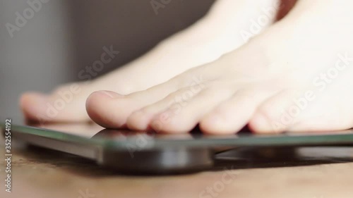 A woman measures her weight on a bathroom scale. Young woman gets up on the scales close-up.