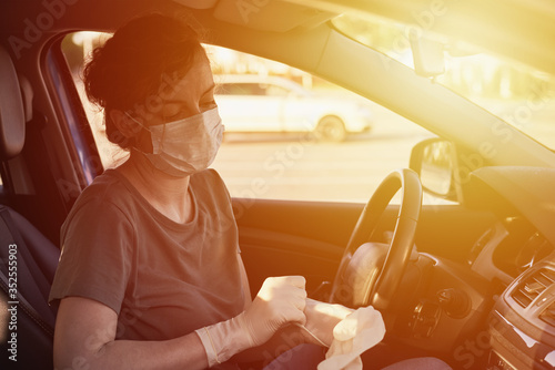 Woman in protective mask and medicine gloves driving a car. Protection from virus epidemic and infection