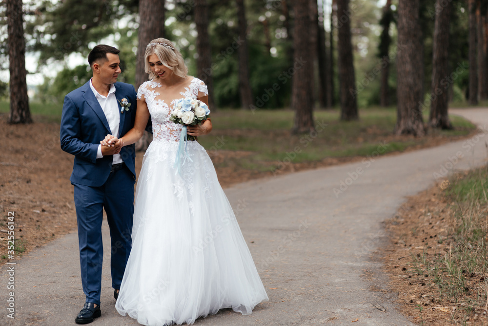 Smiling bride and groom walking in the park