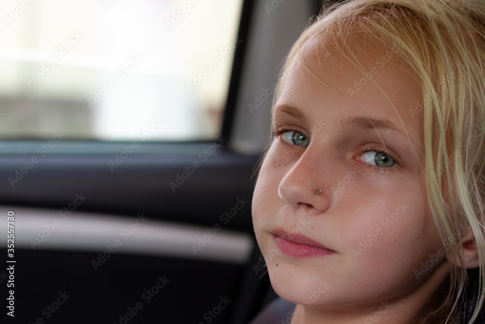 Closeup portrait of a relaxed and calm car passenger. A beautiful young blond girl is enjoying the journey in the car. Copy space. Travel by car. Portrait of cute child at the window of a moving auto. Closeup portrait of a relaxed and calm car passenger. A beautiful young blond girl is enjoying the journey in the car. Copy space. Travel by car. Portrait of cute child at the window of a moving auto.