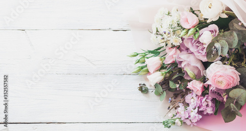 a large and beautiful bouquet of fresh roses, eustoma, matiola, freesia, eucalyptus, hydrangea in delicate pink and white colors, on a white wooden background in the style of Provence. Copy space.