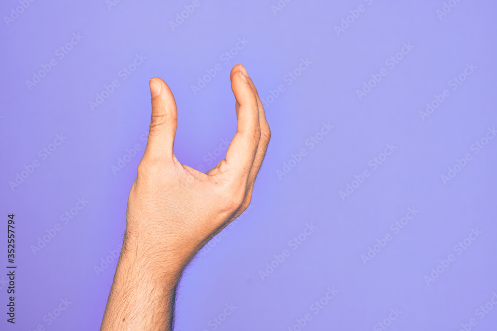 Hand of caucasian young man showing fingers over isolated purple background picking and taking invisible thing, holding object with fingers showing space Hand of caucasian young man showing fingers over isolated purple background picking and taking invisible thing, holding object with fingers showing space