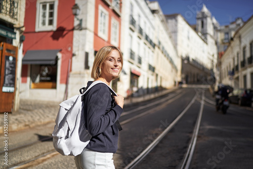 Traveling by Portugal. Happy young woman with rucksack walking by streets in Lisbon. © luengo_ua
