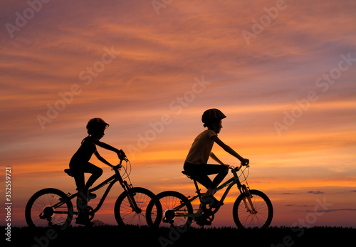 silhouettes of children on bicycles against the background of the sunset