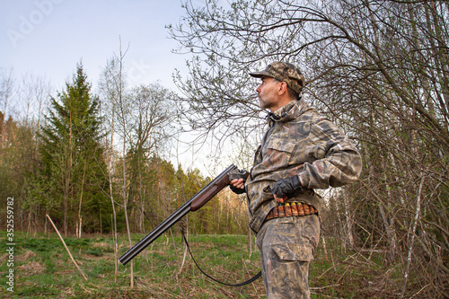 the hunter takes a cartridge from the cartridge belt to load the shotgun