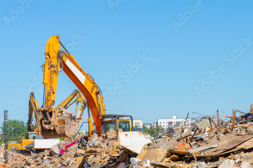 Destruction of old building. Yellow excavator on ruins. 