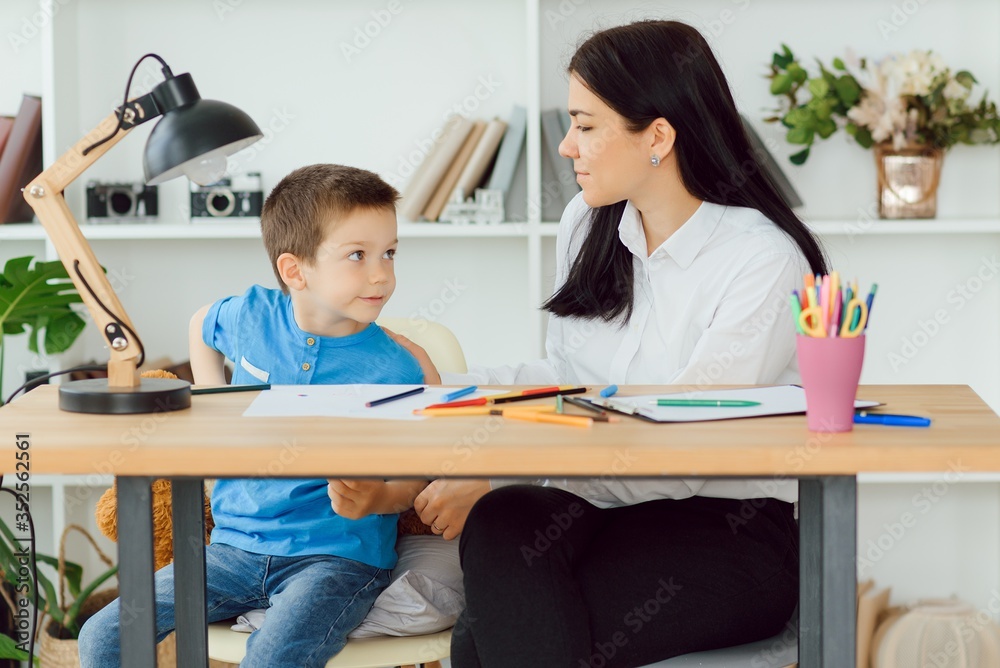 Young female psychologist working with little boy in office Young female psychologist working with little boy in office