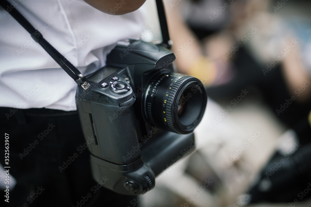 Photographer hanging DSLR camera on shoulder, photography concept professional photographer