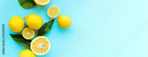 Ripe juicy lemons and green leaves on bright blue background. Lemon fruit, citrus minimal concept, vitamin C. Creative summer food minimalistic background. Flat lay, top view, copy space,banner