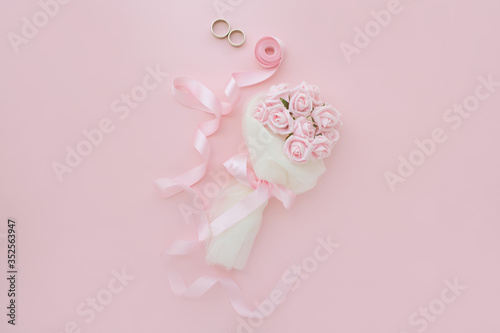 Wedding background top view of the bride's bouquet of pink roses and pink ribbon. Concept delicate female backgrounds or photos for a wedding.