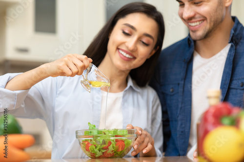 Happy young couple preparing salad together at home