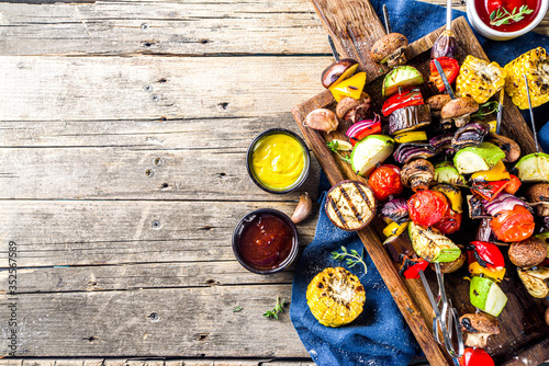 Vegan barbecue party fest concept. Whole vegetable diet kebabs set of various vegetables on skewers. Grilled vegetables on skewers - zucchini, tomato, pepper, eggplant, mushrooms, with sauces