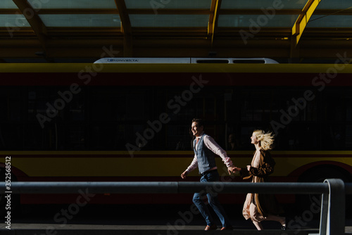 A young woman and a man are running near the bus.