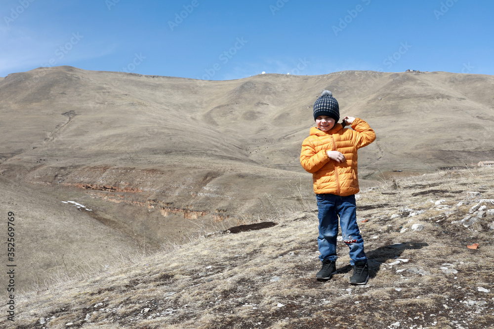 Boy posing on rocky ridge of Caucasus background