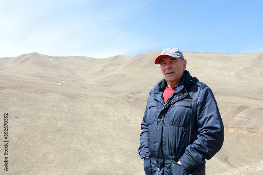 Senior man posing on rocky ridge of Caucasus background Senior man posing on rocky ridge of Caucasus background