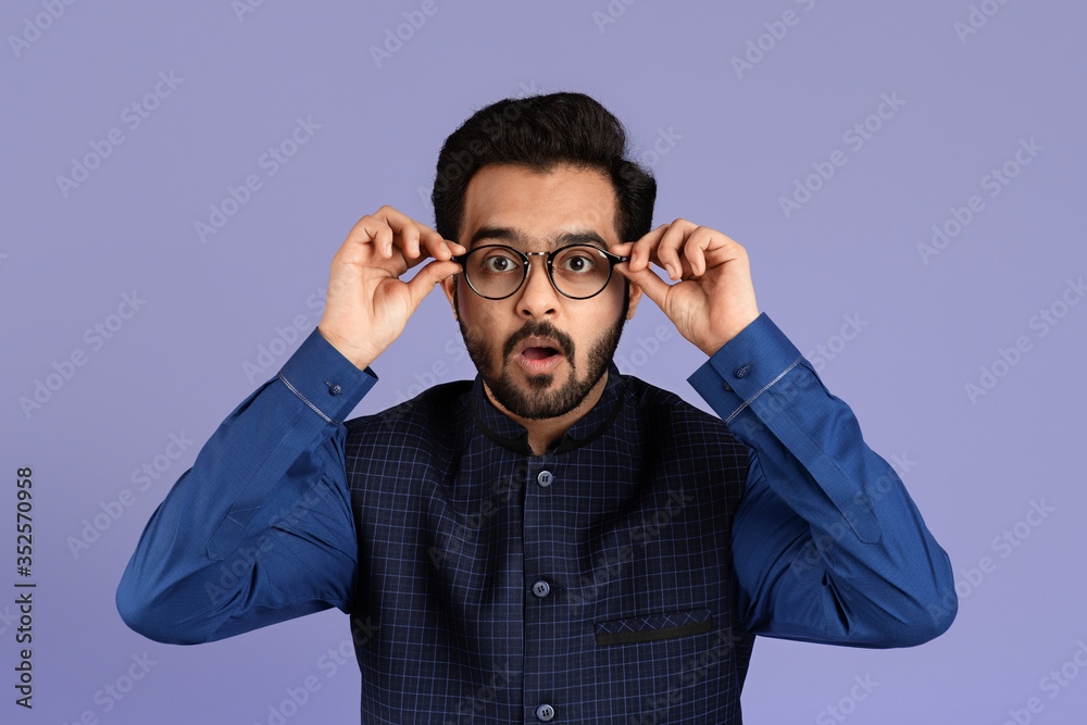 Millennial Indian guy opening mouth in surprise on lilac background Millennial Indian guy opening mouth in surprise on lilac background