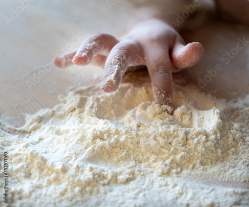 the fingers of a child's hand play with white flour