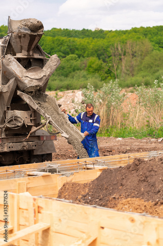 Construction worker laying cement or concrete into the foundation formwork