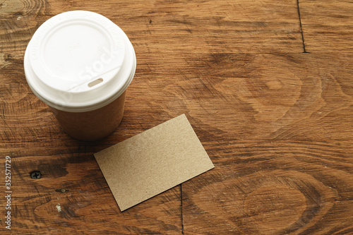 Bild auf Leinwand Takeaway coffee cup with blank business card on wooden table