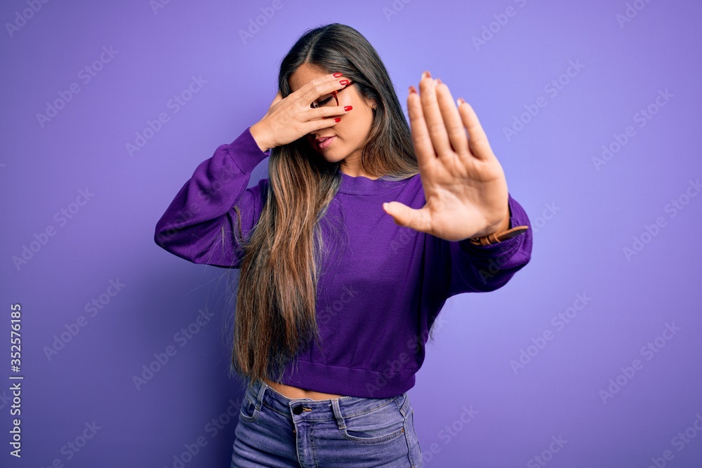 Young beautiful smart woman wearing glasses over purple isolated background covering eyes with hands and doing stop gesture with sad and fear expression. Embarrassed and negative concept.