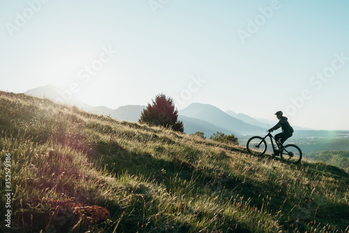 Photos Athletic man pedalling an MTB E-bike up a steep grassy hill