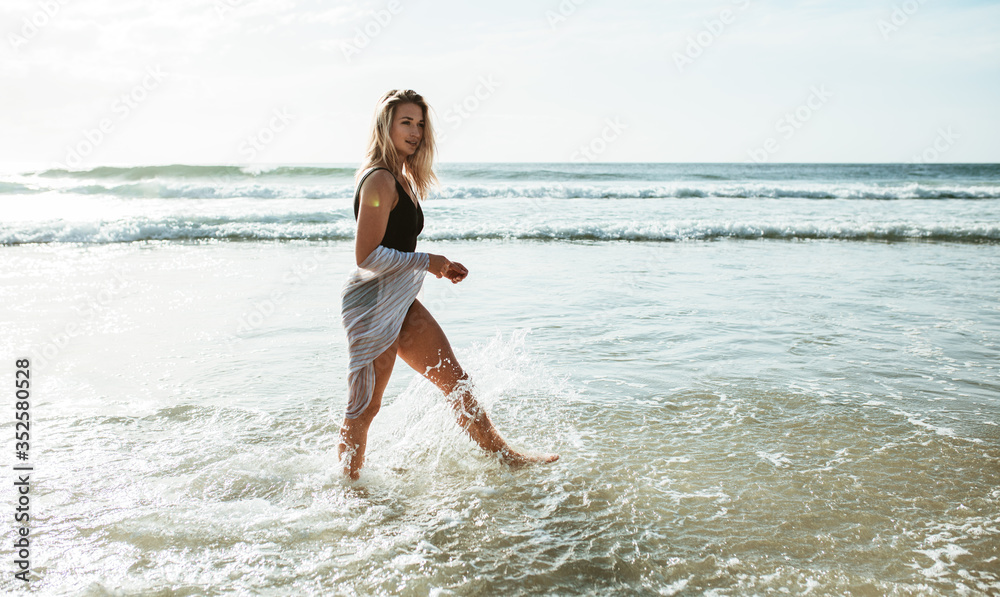 Fototapeta premium Woman walking in water at the beach