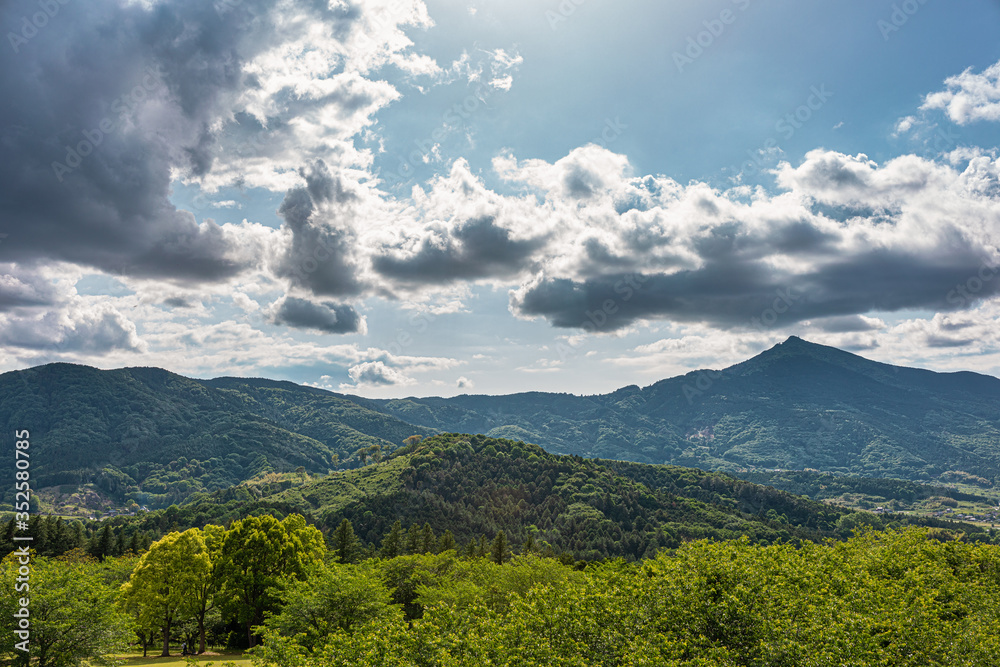太陽光に照らされた大きな雲と新緑の里山 太陽光に照らされた大きな雲と新緑の里山