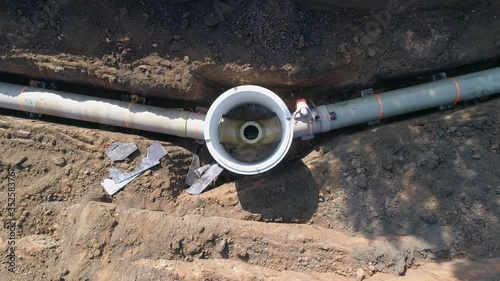Concrete pipe tube installation. Aerial above men at work outside with heavy machinery to connect and install water or sewerage pipeline in a digging soil land