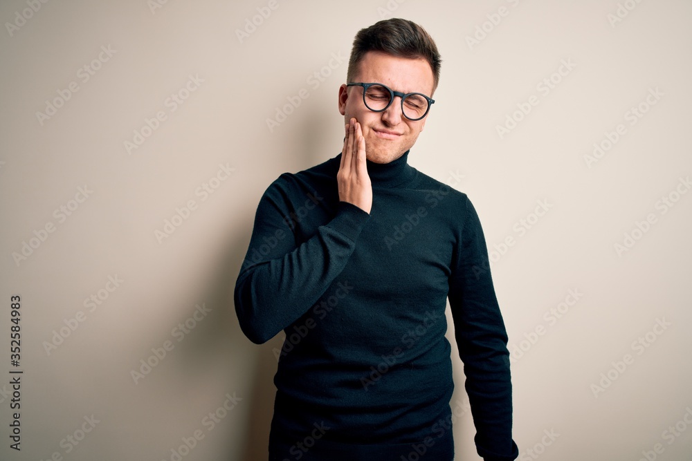 Young handsome caucasian man wearing glasses and casual sweater over isolated background touching mouth with hand with painful expression because of toothache or dental illness on teeth. Dentist Young handsome caucasian man wearing glasses and casual sweater over isolated background touching mouth with hand with painful expression because of toothache or dental illness on teeth. Dentist