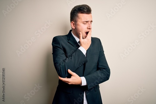 Young handsome business man wearing elegant suit and tie over isolated background bored yawning tired covering mouth with hand. Restless and sleepiness.