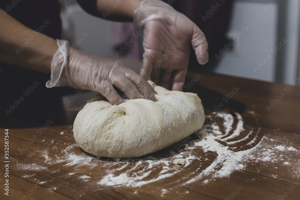 Hands of a woman making dough with plastic gloves on the table Hands of a woman making dough with plastic gloves on the table