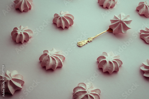 Biscuit pastry on a golden dessert plate near rows of the same sweets on a pink background.