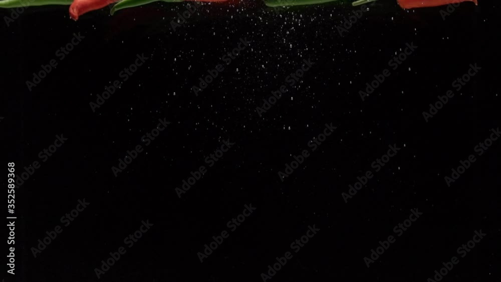peppers fall into water in slow motion. on a black background peppers fall into water in slow motion. on a black background