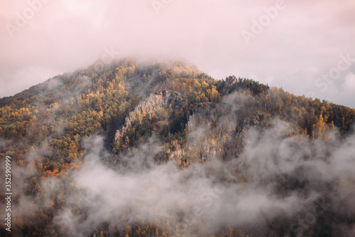 Wonderful view of autumn landscape above in the Urals mountains under white air clouds 