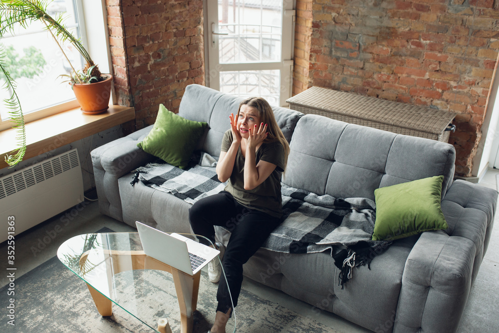 Obraz premium Going crazy. Young woman working or studying at home, looking on computer screen, monitor. Copyspace for your ad. Finance, business, work, gadgets and tech concept. Freelance, education, remote work.