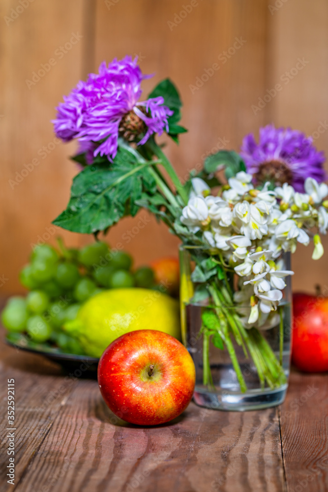 apples, lemon, grapes and flowers on a wooden background apples, lemon, grapes and flowers on a wooden background